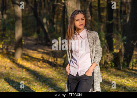 Une jolie fille adolescente pose dans une forêt de chênes de l'automne à l'après-midi. Elle a un air pensif et détaché sur son visage. Banque D'Images