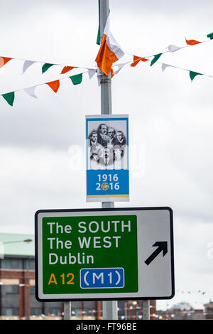 L'Ouest de Belfast, en Irlande. 25 mars, 2016. Vert Blanc et orange et blanc avec le Sinn Fein affiches et le signe de la circulation au sud, l'Ouest et Dublin attaché à un lampost dans l'Ouest de Belfast. On se prépare à commémorer le 100e anniversaire de l'Insurrection de Pâques Crédit : Bonzo/Alamy Live News Banque D'Images