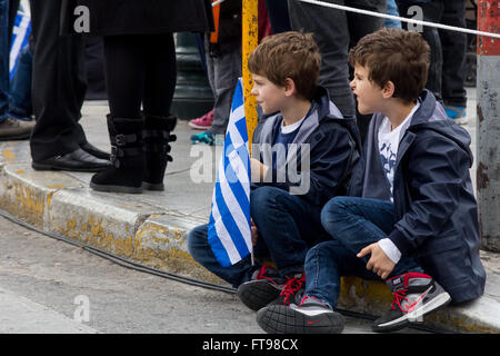 Athènes, Grèce. Mar 25, 2016. Deux enfants de regarder le défilé tenant un drapeau grec. Au 25 mars en raison de la fête de l'indépendance nationale un défilé militaire a eu lieu au centre d'Athènes pour célébrer l'anniversaire de la révolution de la Grèce contre les Turcs occupent au 25 mars 1821. Credit : Kostas Pikoulas Libre prestation/Pacific Press/Alamy Live News Banque D'Images