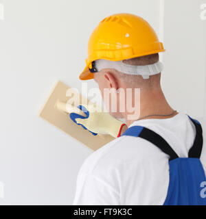 Plâtrier hommes en uniforme le mur de polissage Banque D'Images