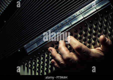 Composition conceptuelle sur la lecture d'un accordéon, les détails d'une main sur un instrument tout en jouant. Banque D'Images