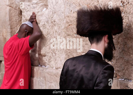 Juif hassidique portant un chapeau de fourrure shtreimel portés par de nombreux hommes mariés communauté juive, le chabbat et les fêtes juives et un Éthiopien juif prie dans le Mur Occidental ou Kotel dans la vieille ville de Jérusalem-Est Israël Banque D'Images