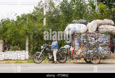 Recyclage plastique surchargée. Une petite remorque moto remorque un énorme surchargé de bouteilles en plastique le long de la route Banque D'Images