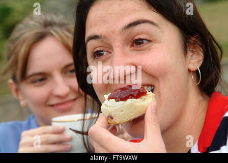 Deux femmes de manger une crème Devon le thé avec des scones et de la confiture, crème,à l'extérieur dans un jardin.un repas à l'heure du thé britannique Banque D'Images