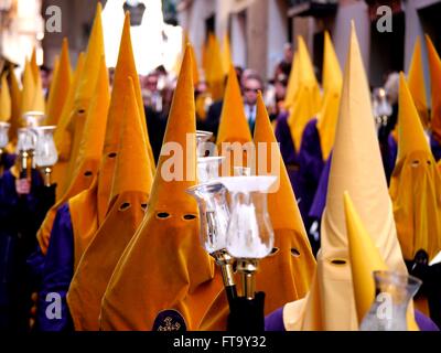 Pénitents catholiques appartenant à un Cofradias confréries religieuses ou traditionnelles, portez des drôles d'aspiration et d'effectuer au cours d'une croix de procession de Pâques dans le cadre des célébrations de la Semaine Sainte de Malaga, en Espagne. Banque D'Images