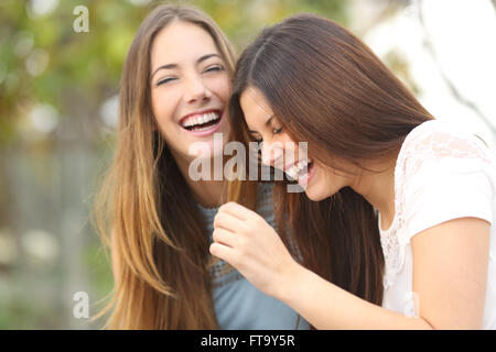 Deux amis femme heureux rire ensemble dans un parc avec un fond vert Banque D'Images