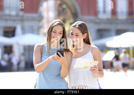 Deux amis touristiques consulter un guide en ligne sur un téléphone intelligent dans la rue Banque D'Images