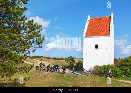 Les jeunes sur un vélo voyage à l'Église en Sand-Covered Skagen Banque D'Images