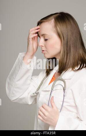 Profil d'une femme médecin fatigué hand on head Banque D'Images