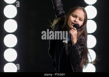 Young Girl singing rockstar en face de stage lights Banque D'Images