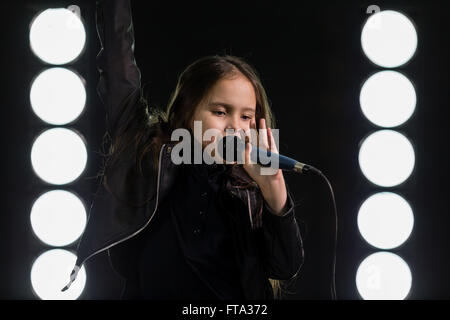 Young Girl singing rockstar en face de stage lights Banque D'Images