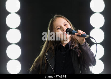 Young Girl singing rockstar en face de stage lights Banque D'Images