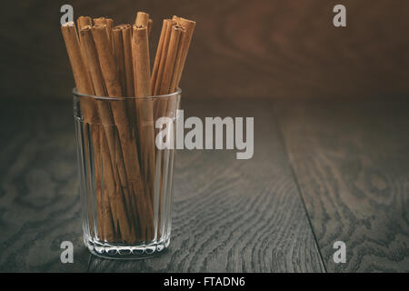 Vrai Les bâtons de cannelle dans le verre sur la table en bois Banque D'Images