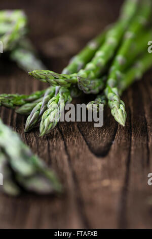 Asperges vertes (fraîches) récoltés sur une vieille table en bois (selective focus) Banque D'Images