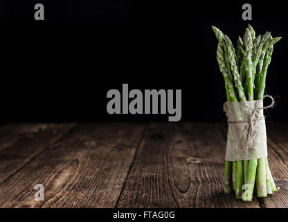 Asperges vertes (fraîches) récoltés sur une vieille table en bois (selective focus) Banque D'Images