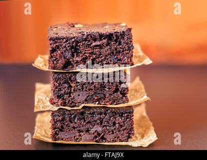 Trois pépites de chocolat brownies empilés sur le papier parchemin. Banque D'Images