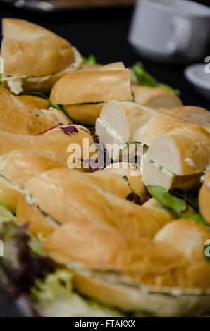 Un bac de bagels coupés en deux et remplis avec du fromage à la crème et ciboulette. Banque D'Images