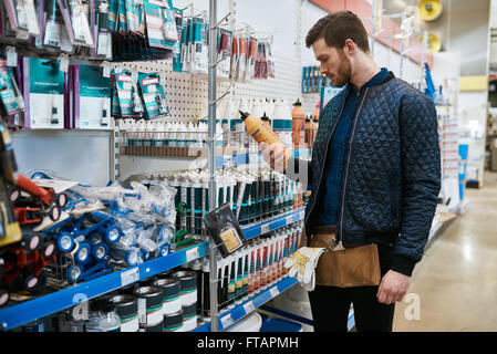 Handyman ou propriétaire d'un magasin de bricolage en date du choix d'un produit dans le ministère et la lecture de l'étiquette Banque D'Images