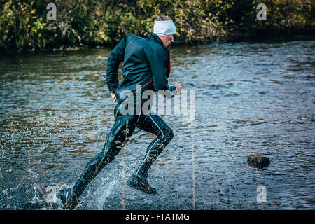 Beloretsk, Russie - le 26 septembre 2015 : l'athlète masculin de traverser la rivière sur les rochers Vue de côté au cours de la montagne marathon Banque D'Images