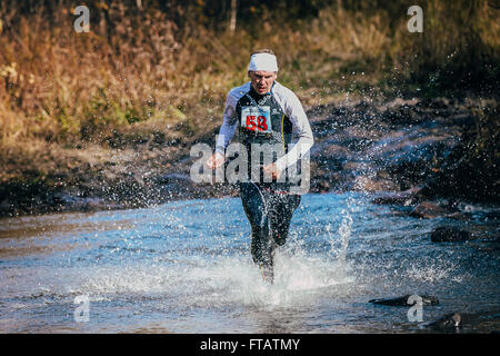 Beloretsk, Russie - le 26 septembre 2015 : runner middle-aged man crossing river, et autour de lui, les projections d'eau lors de marathon Banque D'Images