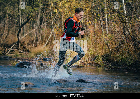 Beloretsk, Russie - le 26 septembre 2015 : Jeune homme runner splash en rivière, au cours d'un passage de la rivière de montagne Banque D'Images