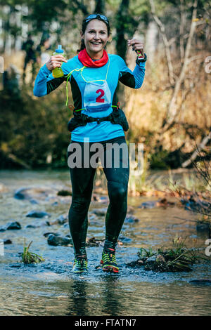 Beloretsk, Russie - le 26 septembre 2015 : young woman smiling runner en traversant une rivière de montagne au cours de montagne marathon Banque D'Images