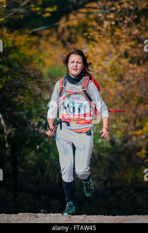 Happy young woman running in autumn Park avec des bâtons de marche nordique en montagne marathon Banque D'Images