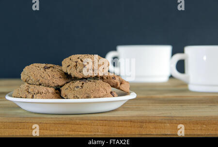 Cookies au chocolat et deux tasses de thé sur une table en bois Banque D'Images