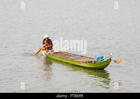 Le pêcheur local dans un bateau en bois, à la recherche après ses filets sur la rivière Bassac dans le Delta du Mékong au Vietnam. Banque D'Images