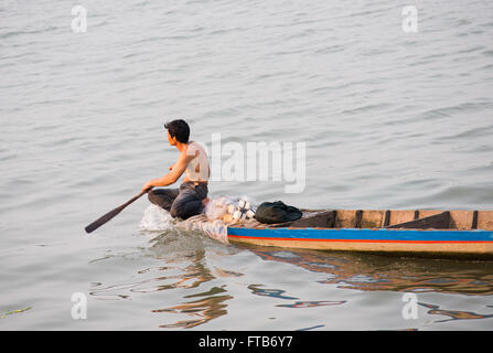 Le pêcheur local dans un bateau en bois, à la recherche après ses filets sur la rivière Bassac dans le Delta du Mékong au Vietnam. Banque D'Images