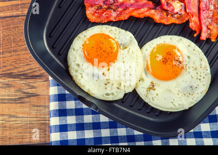 Jambon et oeuf. Bacon et des oeufs. Œuf salé et saupoudré de poivre noir. Petit-déjeuner anglais. Lard grillé, deux œufs dans le moule Banque D'Images