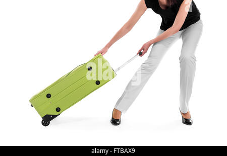 Femme fait glisser une valise lourde sur un fond blanc. Banque D'Images