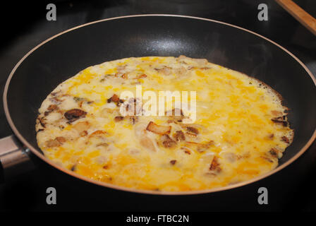 La cuisson des oeufs brouillés ou une omelette aux champignons et oignons Banque D'Images