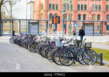 Kristianstad, Suède - 20 mars 2016 : un parc de stationnement pour les vélos à proximité de la gare de voyage dans l'arrière-plan. Les gens qui marchent Banque D'Images