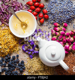 Un plateau/bouilloire de thé en bonne santé, tasse de thé, tisane, herbes médicinales et de petits fruits assortiment sur table. Vue d'en haut. La médecine de fines herbes. Banque D'Images