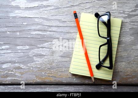 Crayon, lunettes et un bloc-notes sur une table Banque D'Images