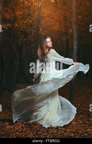 Belle femme dansant dans automne sombre bois. Et la fantaisie surréaliste Banque D'Images