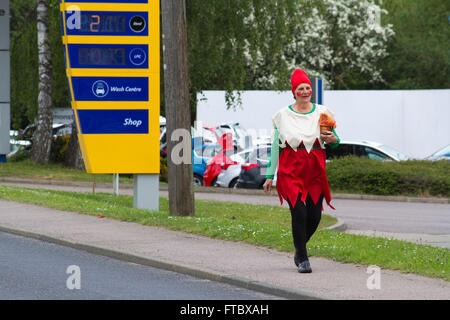 Femme plus âgée portant le costume nain Blanche-neige marche au début d'un défilé de carnaval devant une station-service à Framlingham, une ville de marché du Suffolk. Banque D'Images