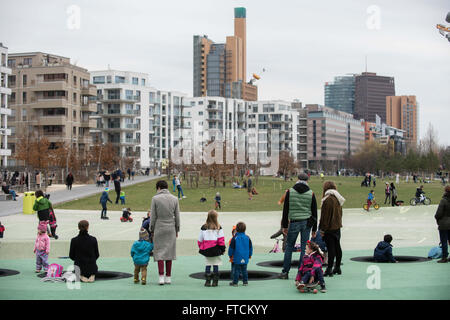 Berlin, Allemagne. Mar 27, 2016. Les enfants et les adultes à l'aire de jeux dans le parc am Gleisdreieck à Berlin, Allemagne, 27 mars 2016, avec la Potsdamer Platz (Place de Potsdam), représenté à l'arrière-plan. Photo : GREGOR FISCHER/dpa/Alamy Live News Banque D'Images