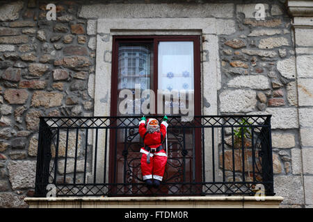 La figure d'un Père Noël gonflable suspendu à balcon de bâtiment en pierre typique, Vigo, Galice, Espagne Banque D'Images