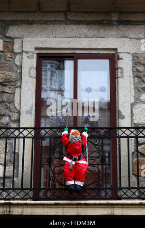 La figure d'un Père Noël gonflable suspendu à balcon de bâtiment en pierre typique, Vigo, Galice, Espagne Banque D'Images