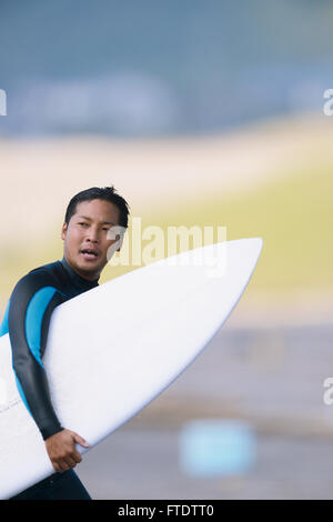 Surfeur japonais marche sur la plage Banque D'Images