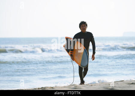 Surfeur japonais marche sur la plage Banque D'Images