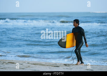 Surfeur japonais marche sur la plage Banque D'Images