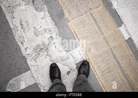 L'homme citadin en noir brillant nouvelles chaussures en cuir sale debout sur le passage pour piétons, signalisation Banque D'Images