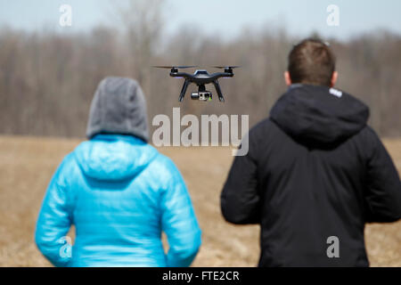 Un couple regardant un drone passez devant eux. Banque D'Images