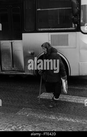 UFA - RUSSIE 1ER MARS 2016 - Une vieille femme utilise un passage pour piétons pour traverser une rue principale perspective octobre qu'un bus se déplacer Banque D'Images