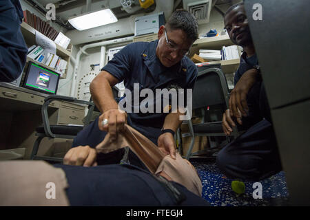 Une photographie prise le 3 octobre 2014, montrant le chef Maître d'armes Joshua Datka appliquant un pansement à une victime simulée lors d'exercices médicaux à bord de l'USS Cole (DDG 67), un destroyer de missiles guidés de l'US Navy. Banque D'Images