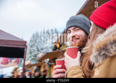 Beau jeune homme barbu souriant de boire du café en plein air avec sa petite amie Banque D'Images