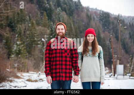 Smiling young couple voyageant dans la forêt d'hiver Banque D'Images